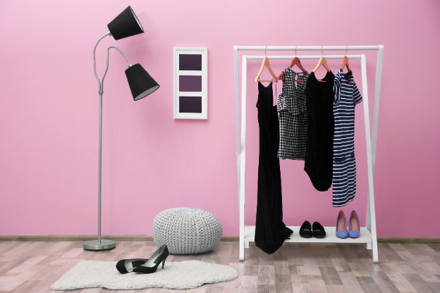Photo of an aesthetic clothing rack containing a few items against a pink backdrop to illustrate showing off your fabric clothing and shoes.