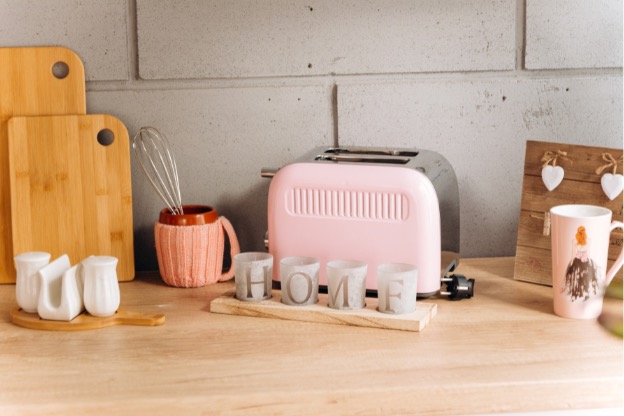 Photo of light pink toaster in cozy, aesthetic kitchen illustrating how to add color to your kitchen with appliances.