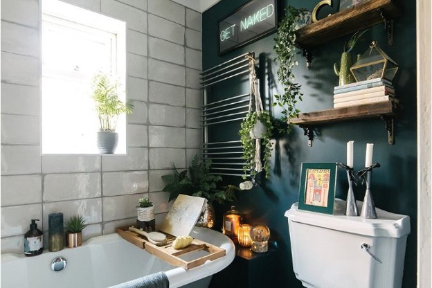 Eclectic bathroom filled with plants, vintage bathtub, toilet, trinkets
